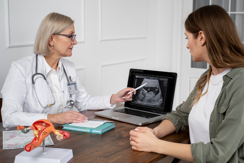 Doctor explaining a fetal ultrasound image to a pregnant woman during a medical consultation