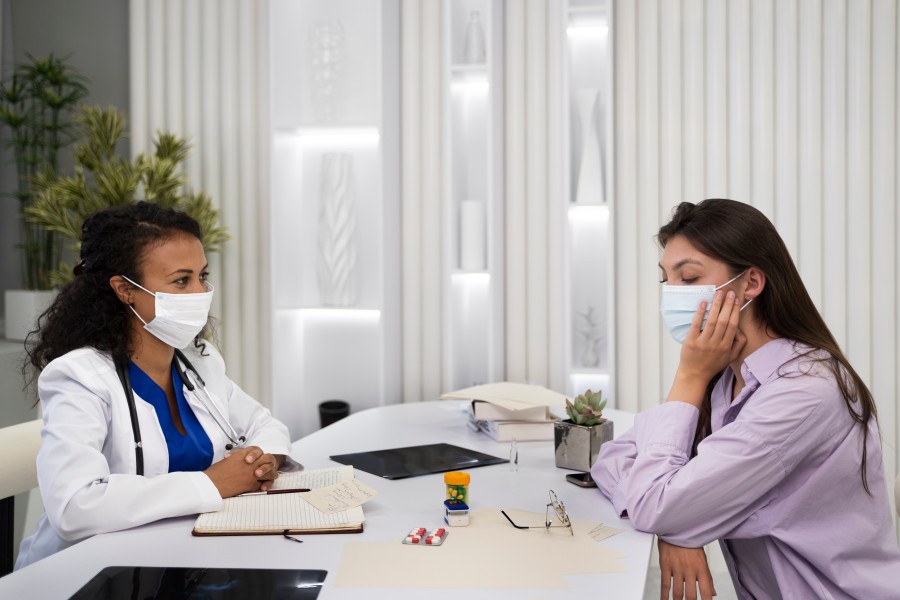 Doctor and patient wearing face masks during a medical consultation in a clinic.
